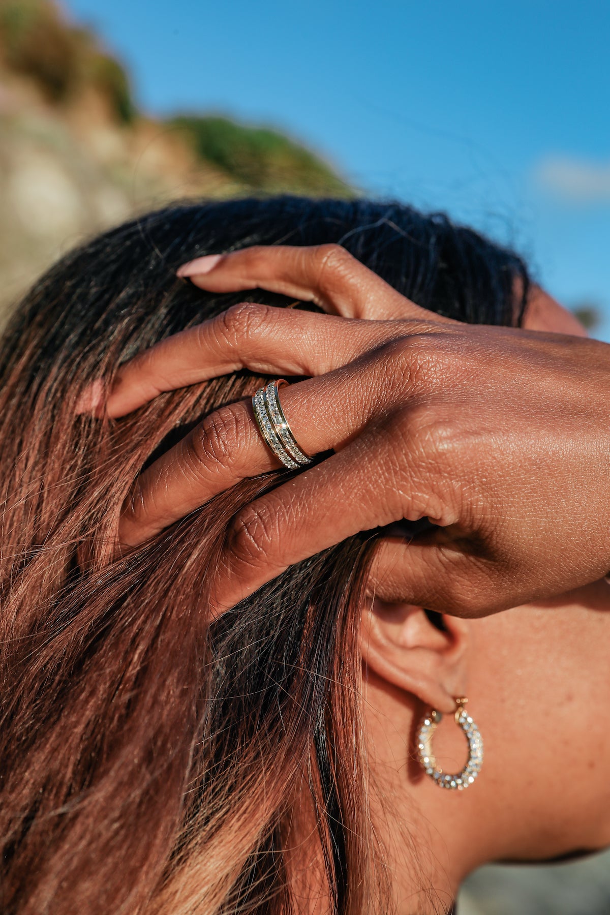 Be extra ring on model hand running through hair paired with girl boss earrings