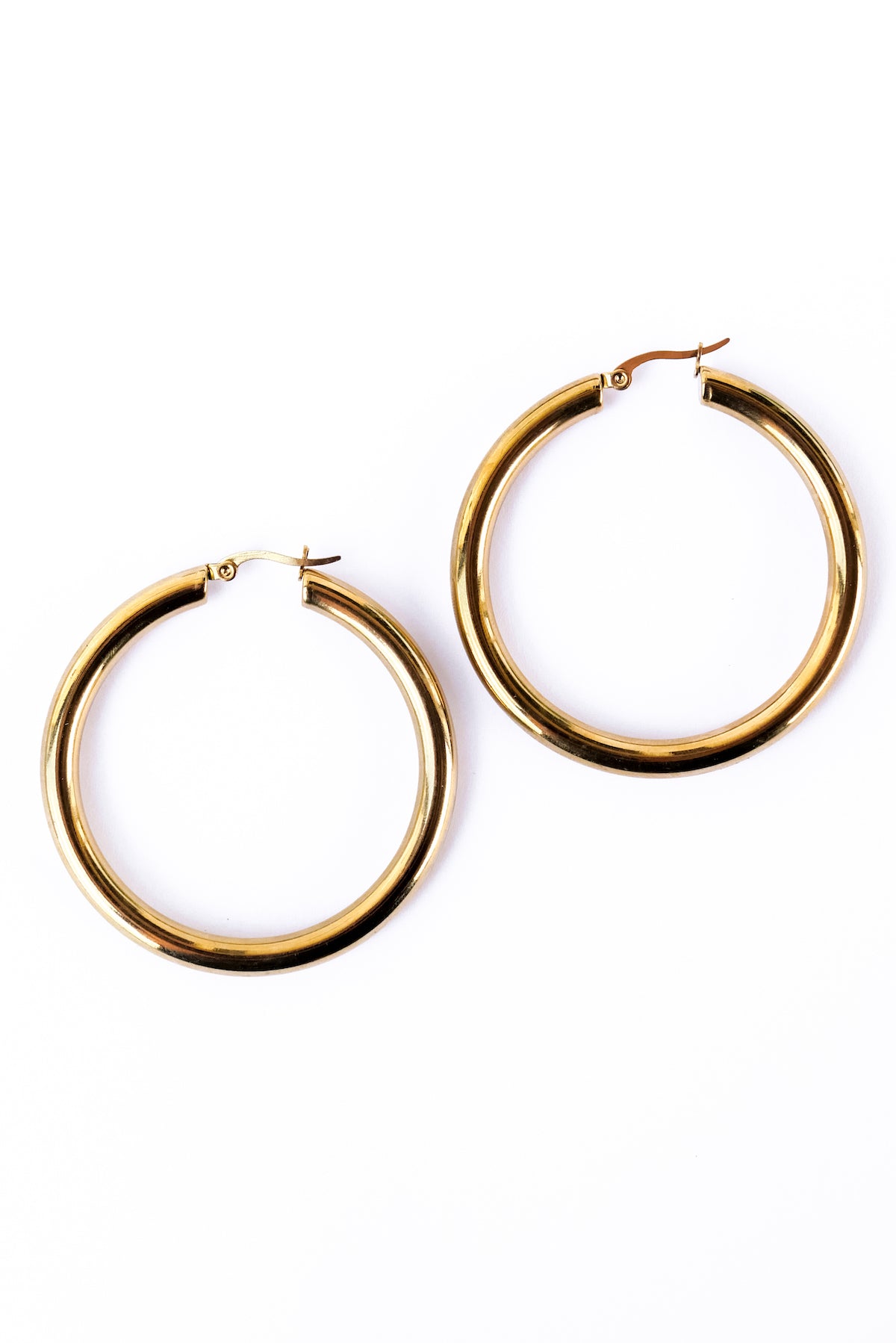 Large staple hoop earrings against a white backdrop