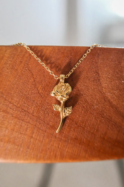 Close up view of carved rosa necklace against a wood backdrop