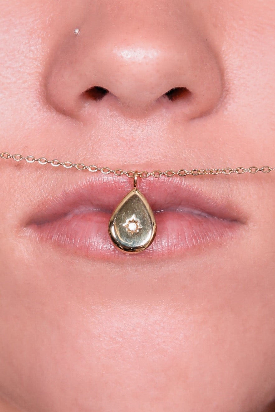 Water drop necklace close up view pressed against a models lips